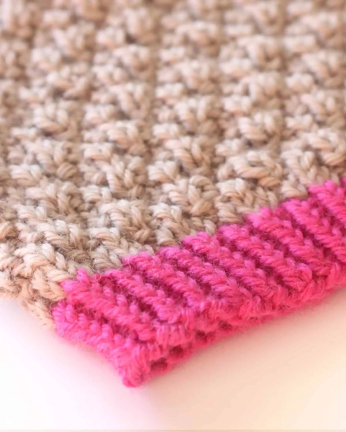 Knitted hat brim with twisted rib stitch in pink colored yarn.