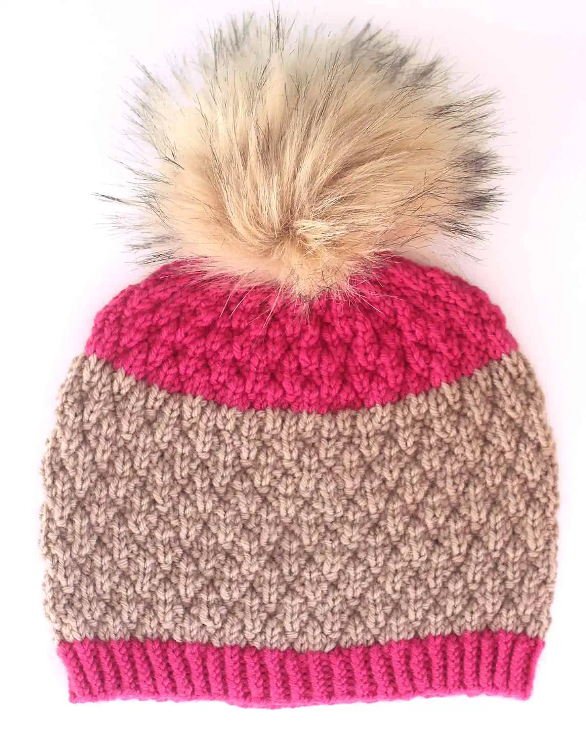 Seersucker knitted hat in tan and pink colored yarns with faux fur pom pom.