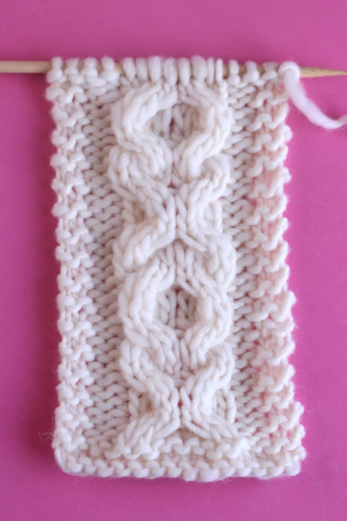 XO Cable textured pattern knitted on straight needles with white colored yarn.