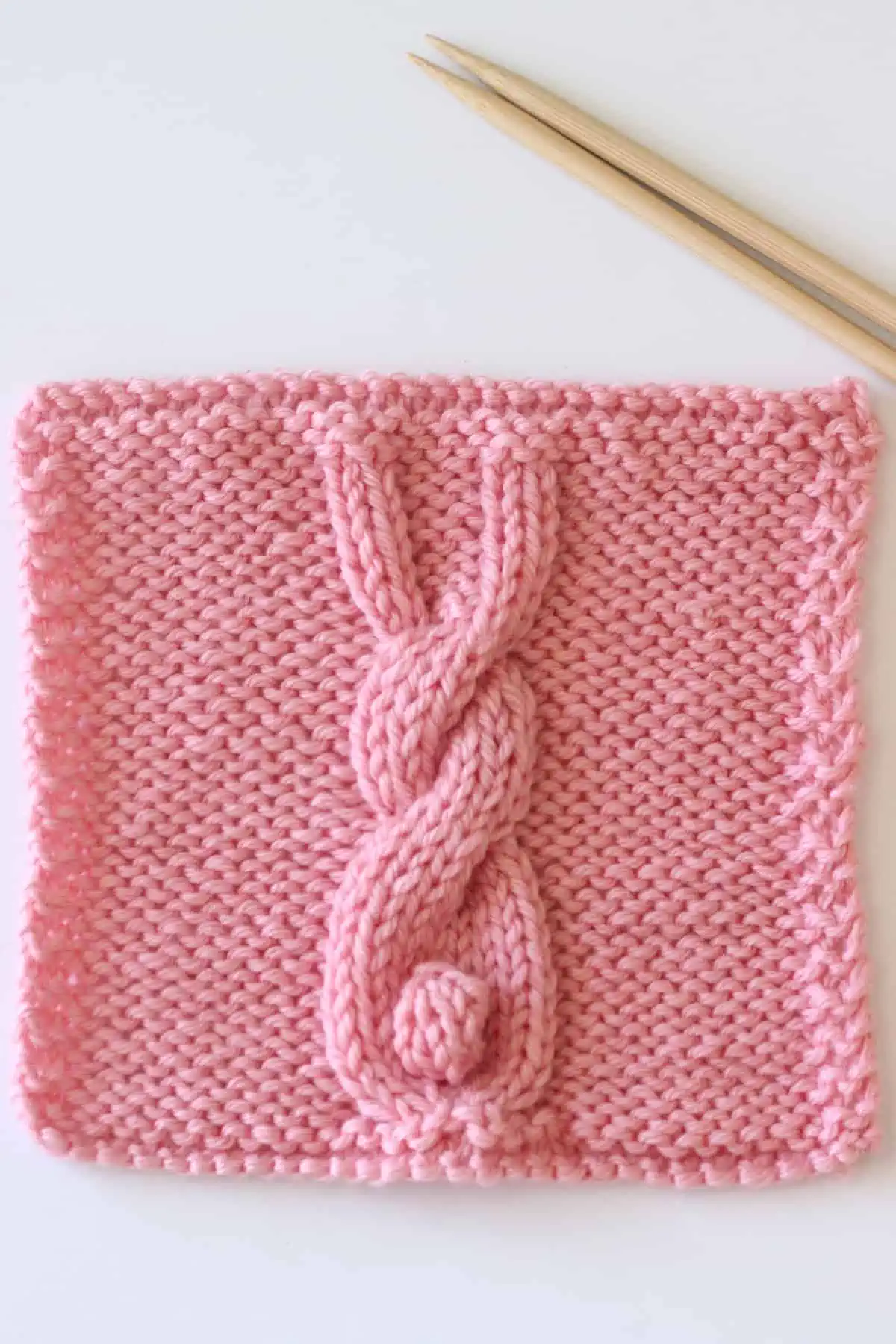 Bunny Cable knitting square in pink yarn color with straight knitting needles.