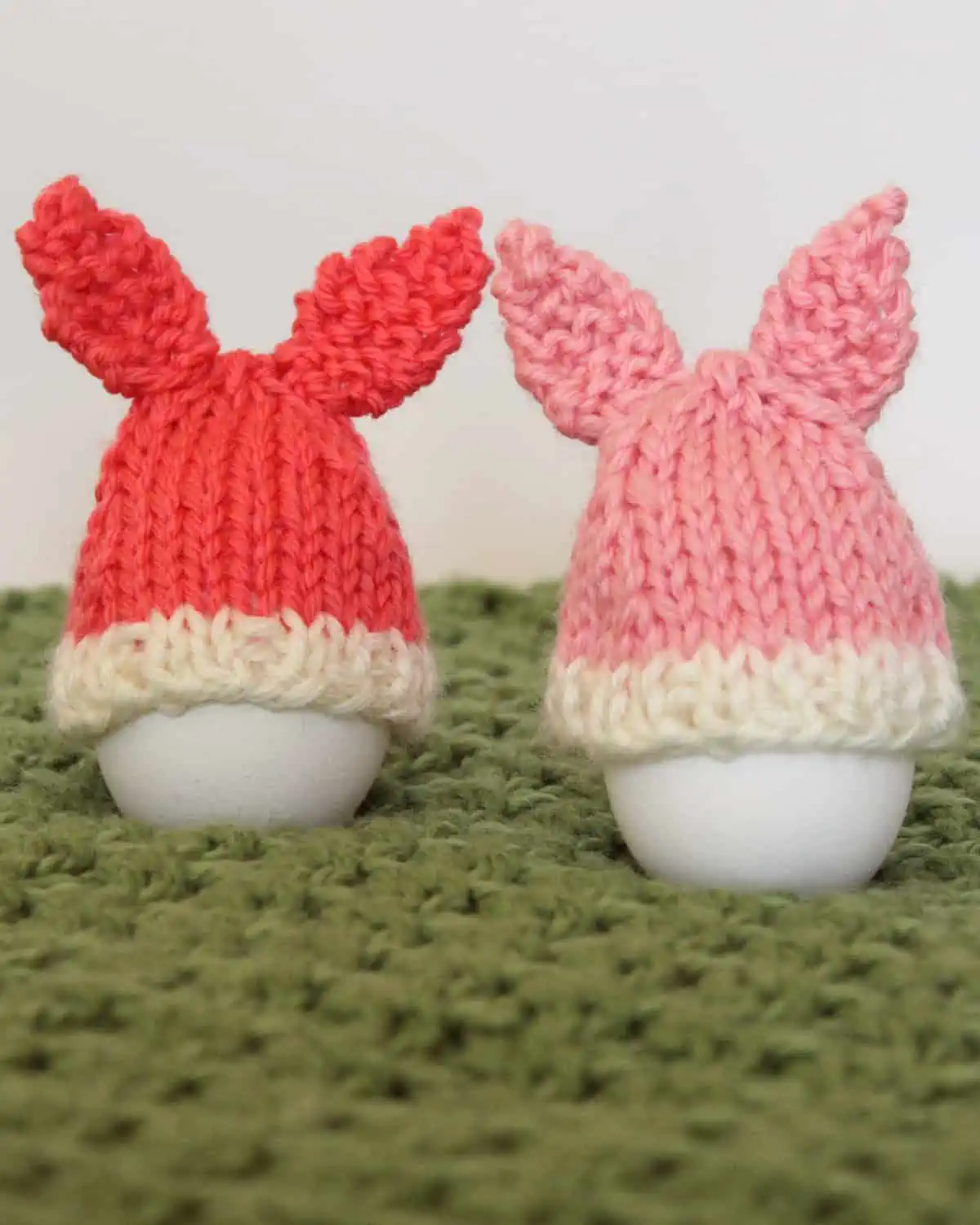 Knitted Bunny Egg Cozies in peach and pink yarn colors.
