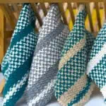 Knitted dishcloths in the linen stitch hanging on a dish rack.