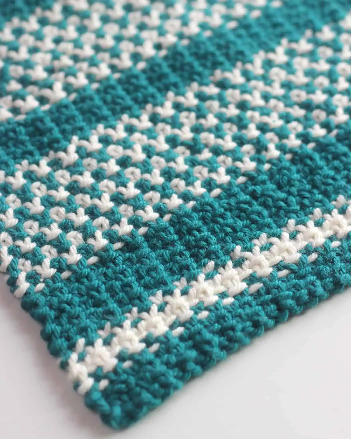 Texture design of the knitted linen stitch dishcloth in blue and white colored yarn.