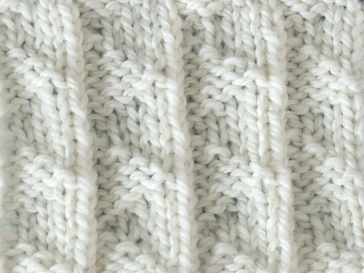 A close up of a white Pennant Pleating knitted stitch.