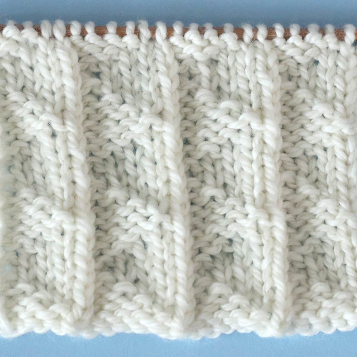 A close up of a white Pennant Pleating knitted stitch.