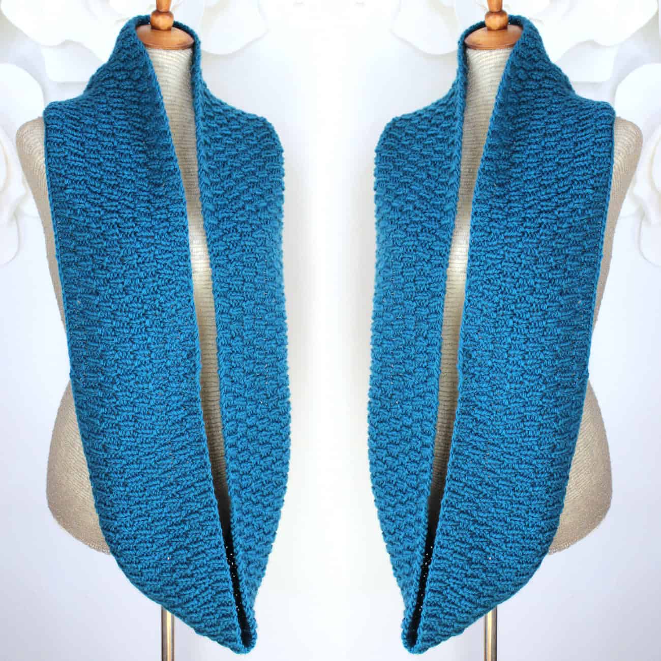 Two infinity scarves draped over mannequin knitted in long raindrop stitch with blue yarn.