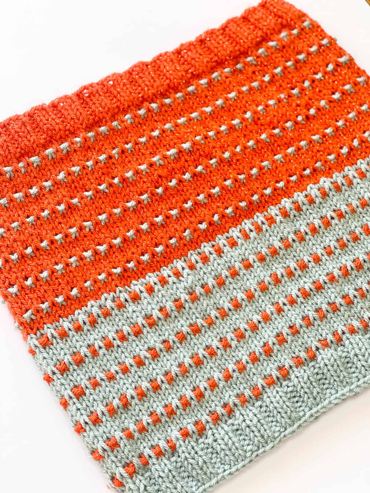 Knitted Soundtrack Cowl with orange sparkle yarn and gray contrast stripes, showing stitch detail.