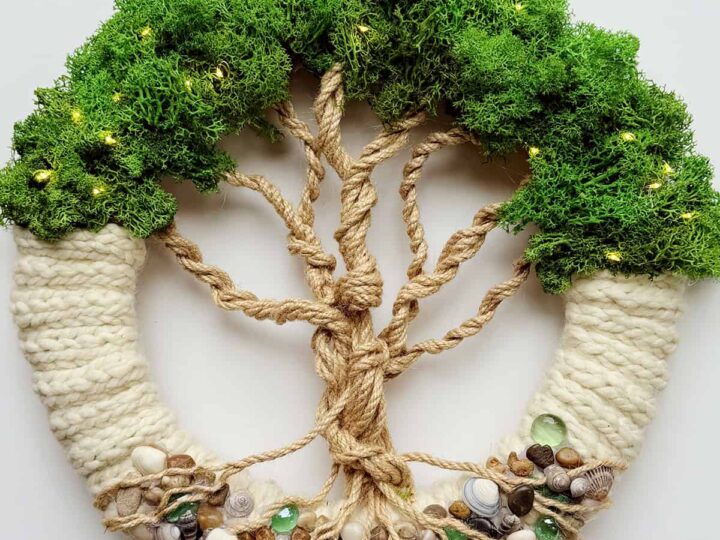 Knitted Tree of Life wreath with moss greenery and rope branches on white background.