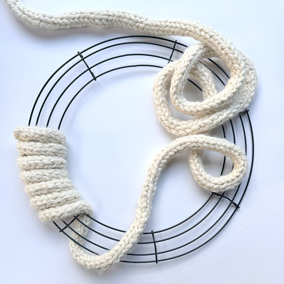 Knitted I-cord wrapped around wire wreath frame to form the base of a Tree of Life wreath before adding branches and decorations.