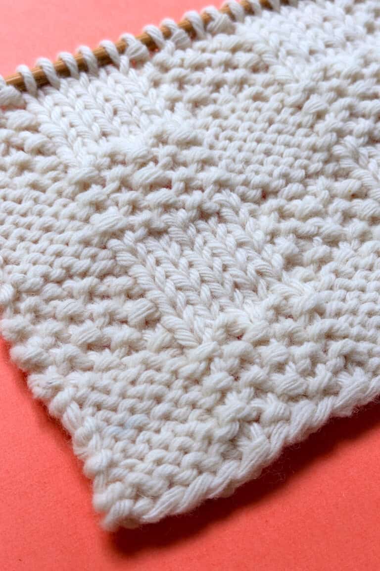 Angled view of Checkerboard Triple Weave Stitch edge on coral background, highlighting flat reversible texture.