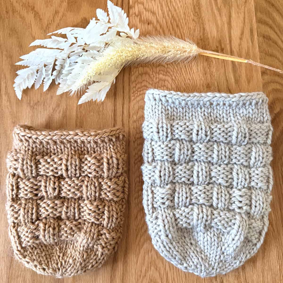 Two Basketweave Mason Jar Cozies in neutral yarn colors with dried floral stems.