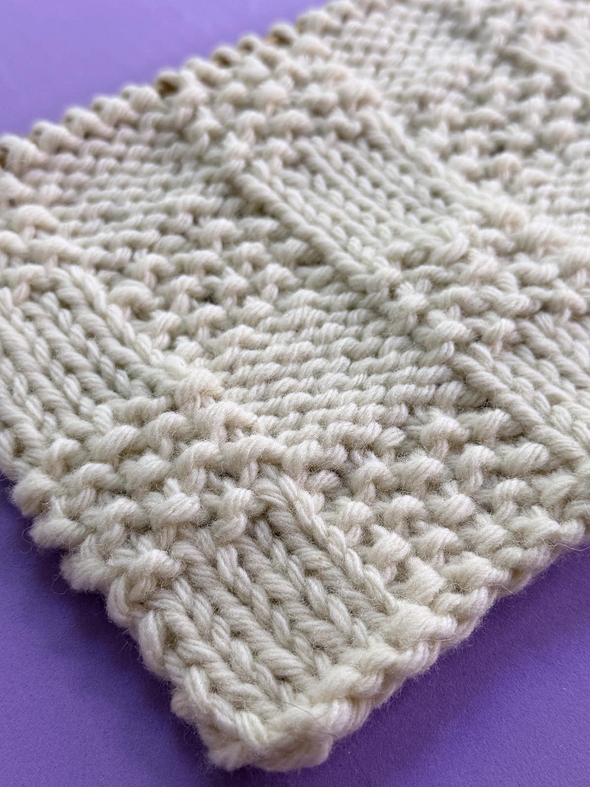 Angled view of Checkerboard Triple Weave Stitch on purple background, with a flat reversible texture.