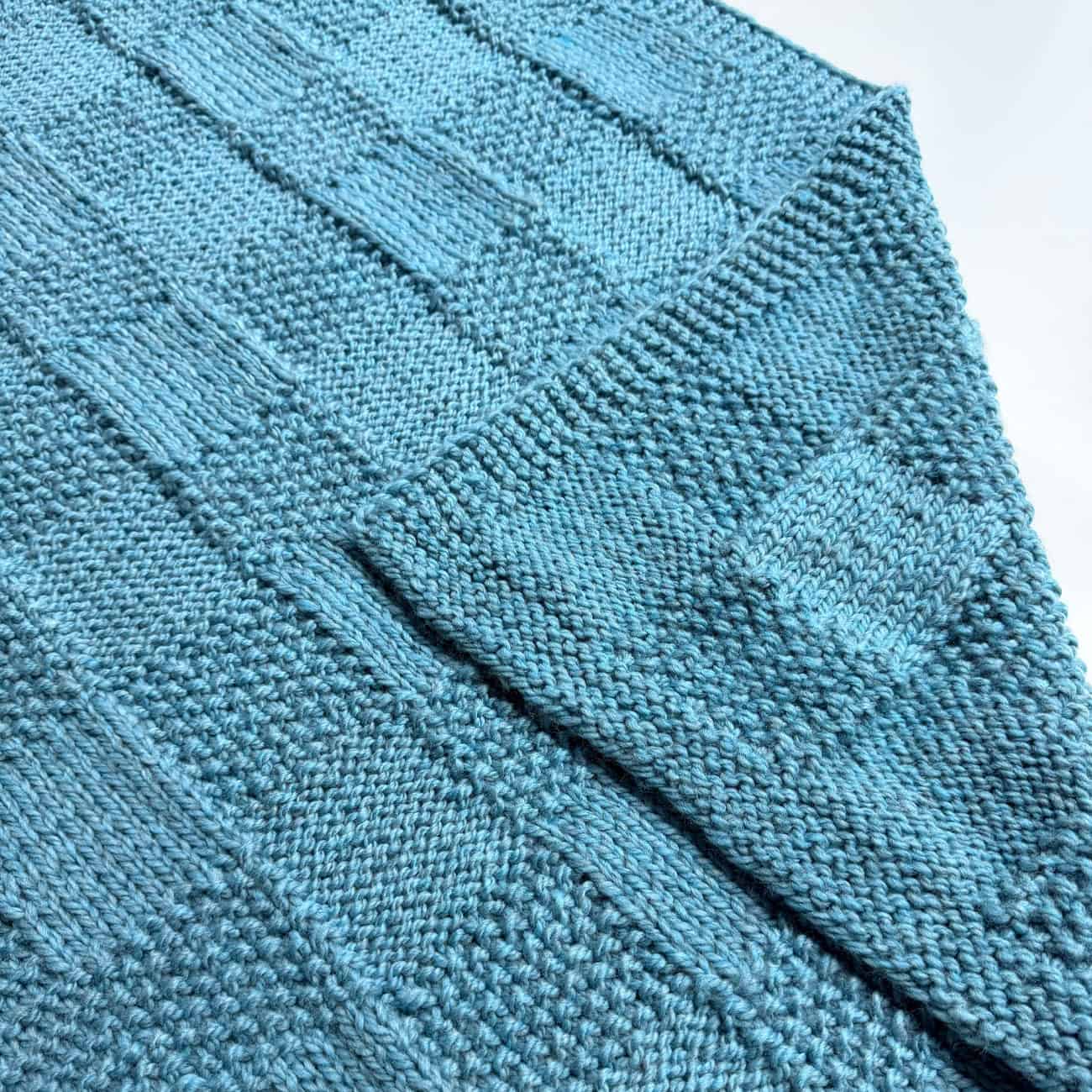 Close-up of blue Pescadero Harvest Blanket folded to show the textured checkerboard stitch pattern.