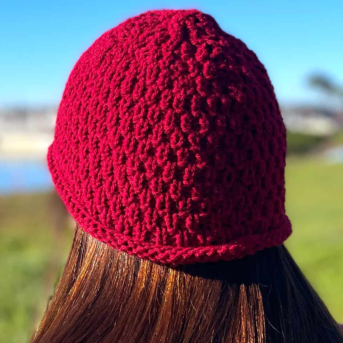 Knitted hat in red yarn in textured Swift Stitch by Studio Knit.